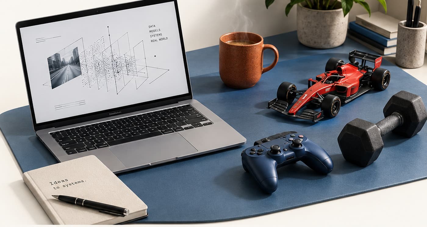 A laptop showing an abstract data-systems diagram, next to a notebook, a tea mug, a model race car, a game controller, and a dumbbell on a desk.